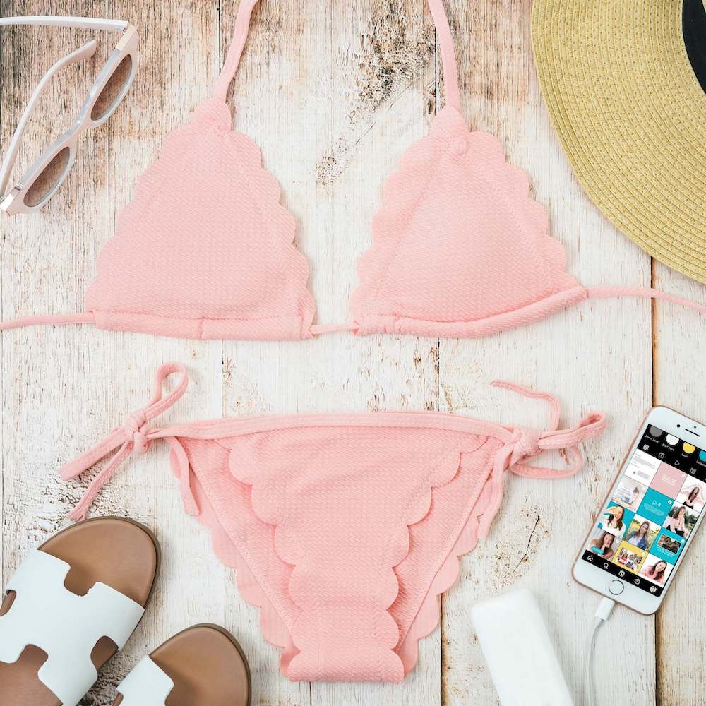 Phone open to Instagram next to a pink bikini and sunhat!